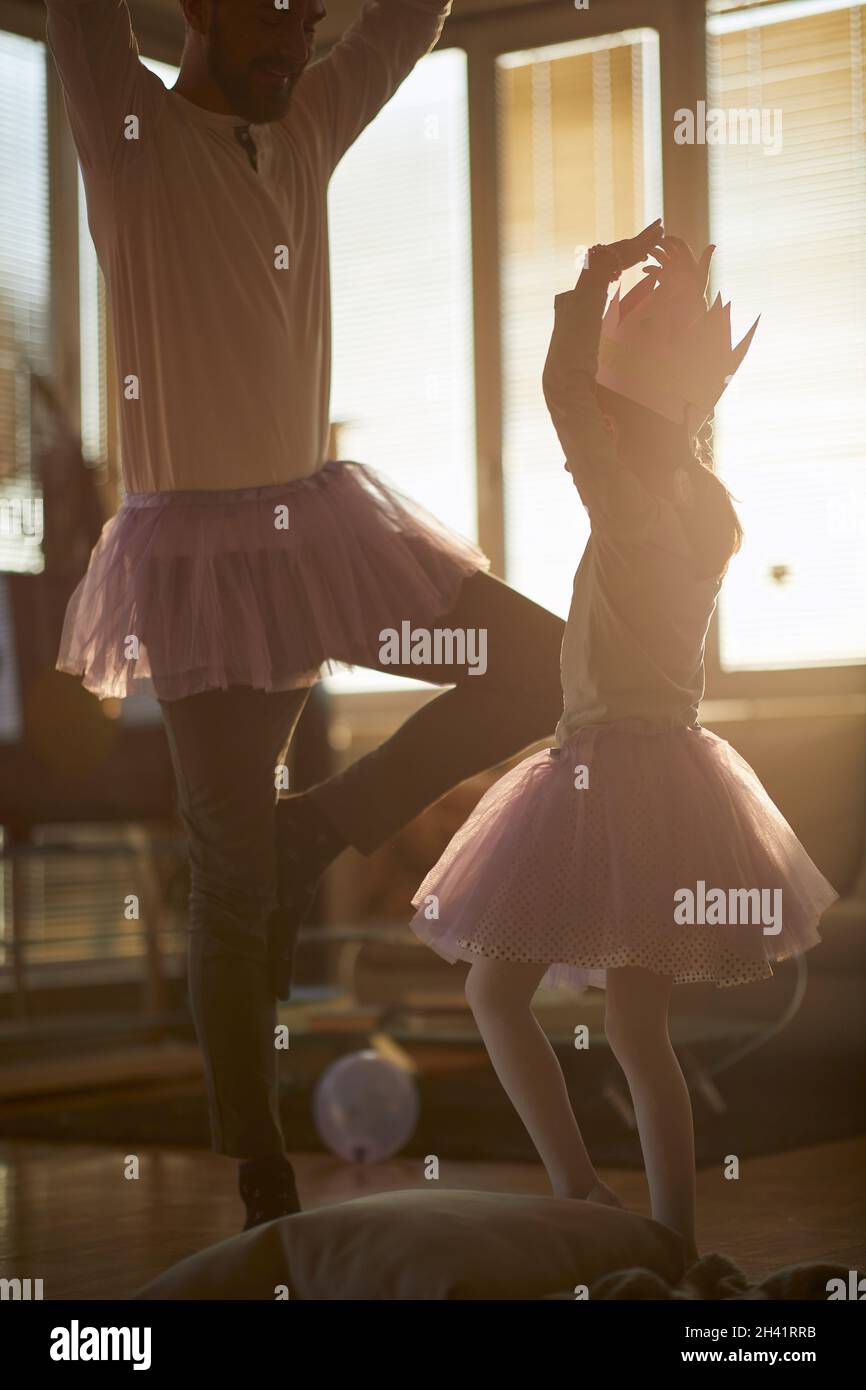 A little ballerina and her father practicing a ballet move at a