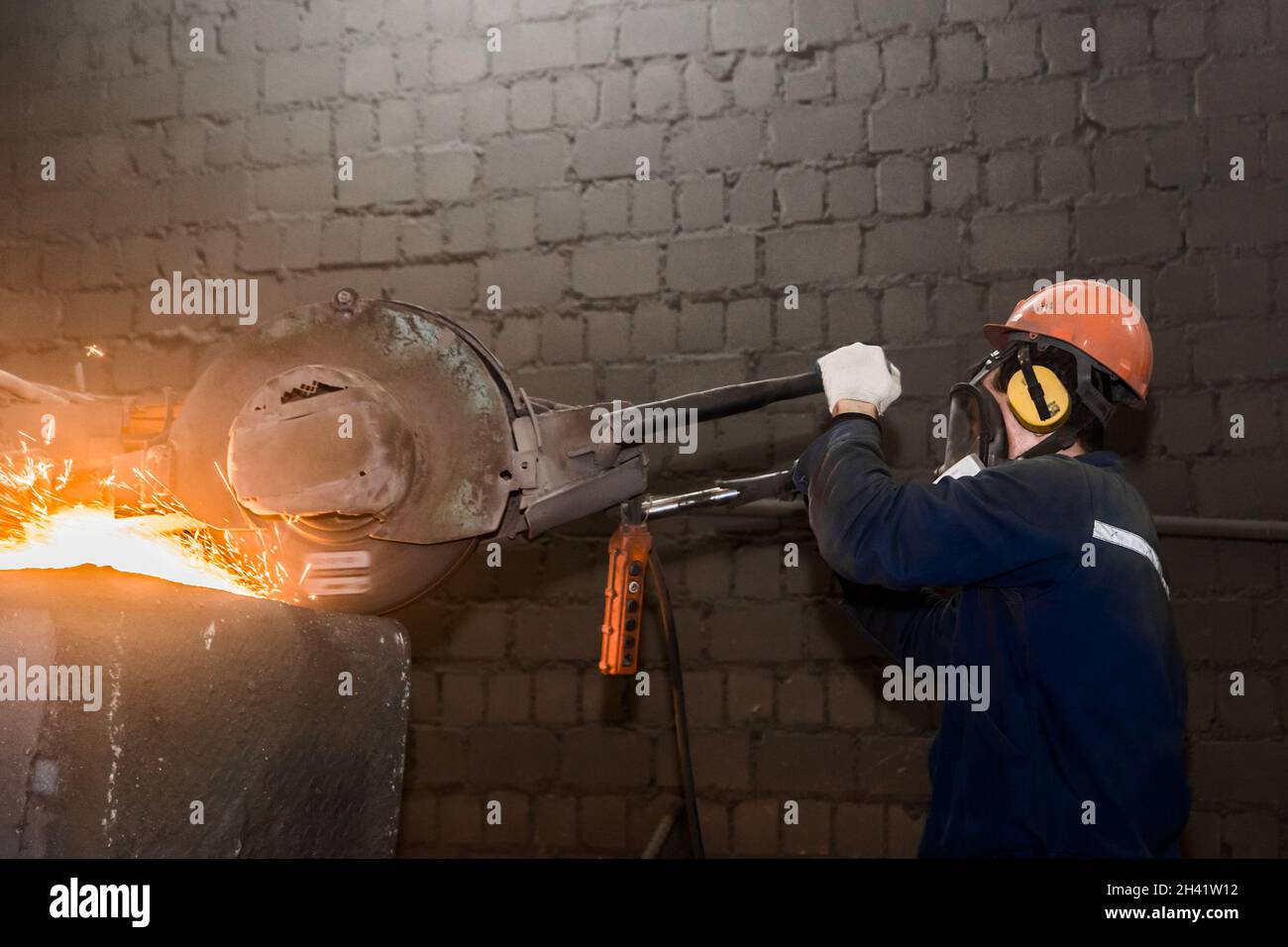 A male worker in a protective helmet, respirator, overalls manages