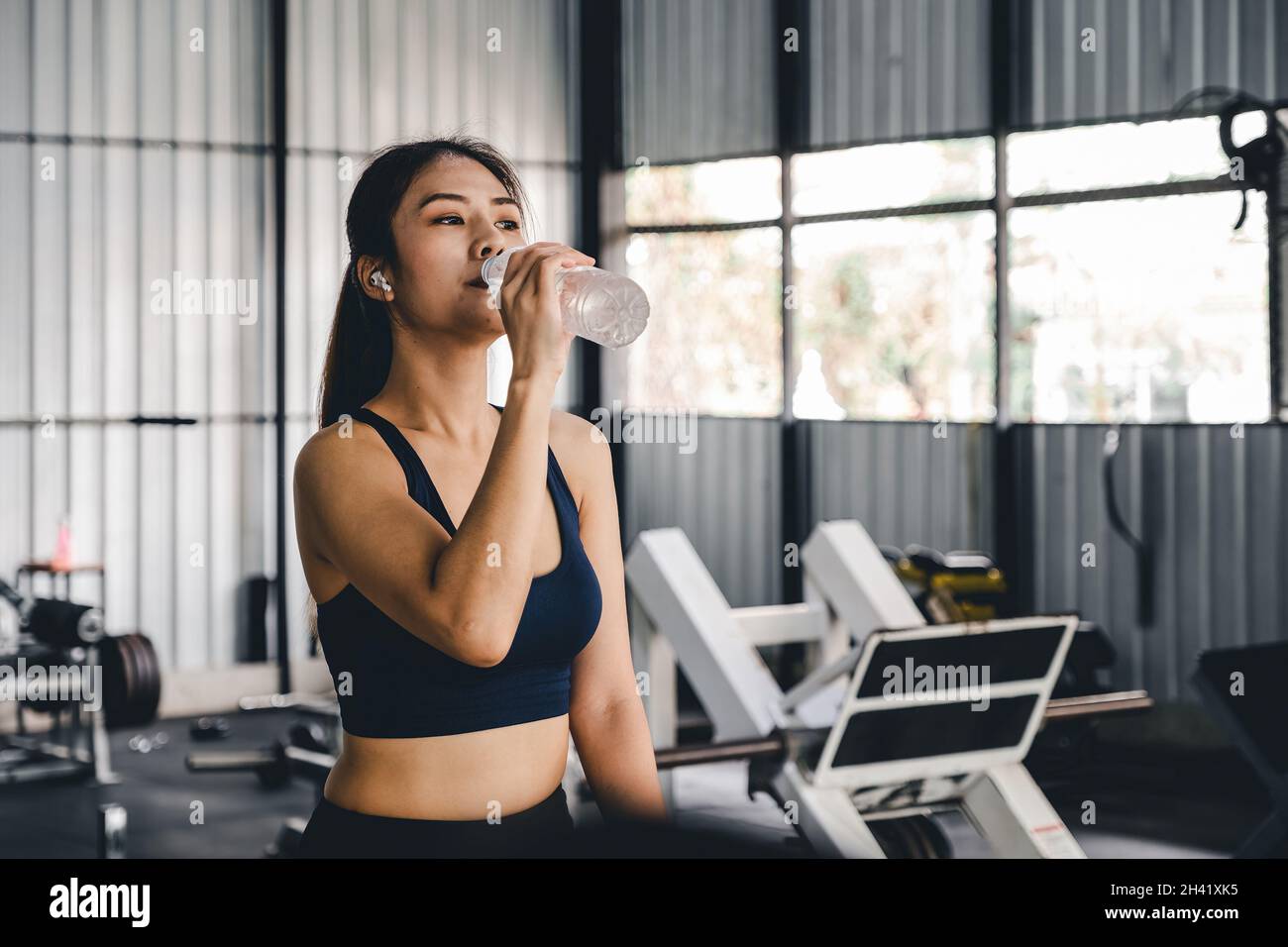 Asian young woman drinking water after workout in gym, healty and sport concept. Stock Photo