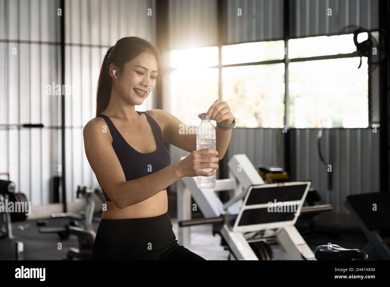 Asian young woman drinking water after workout in gym, healty and sport concept. Stock Photo