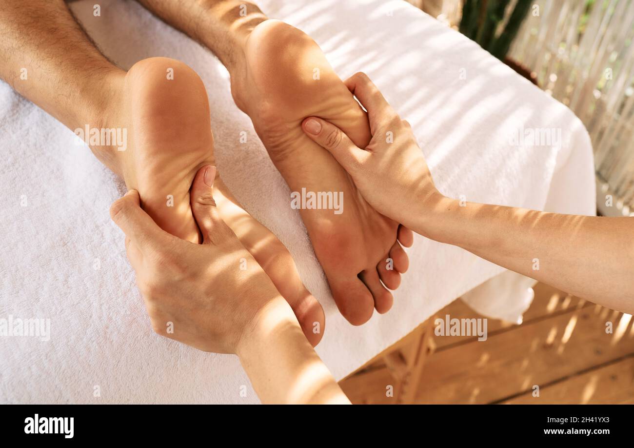 Foot massage with massage oil for male feet while relaxing and resting at spa. Legs massage for man Stock Photo