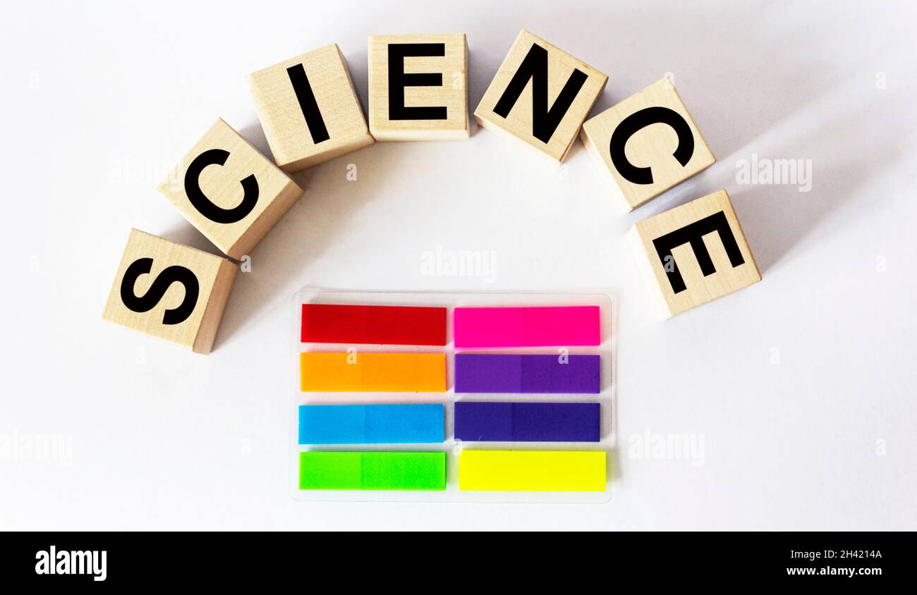 the word science is written on a wooden block. Science text on white table for your design, concept.Near colored stickers Stock Photo