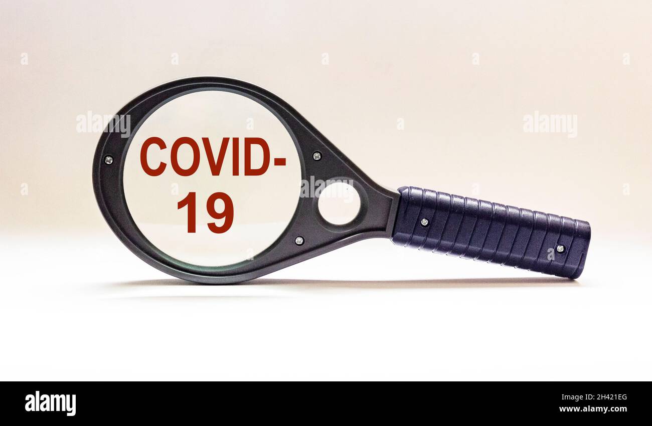 COVID-19 lettering on white background in magnifying glass World Health Organization WHO unveils new official name for coronavirus disease - COVID-19 Stock Photo