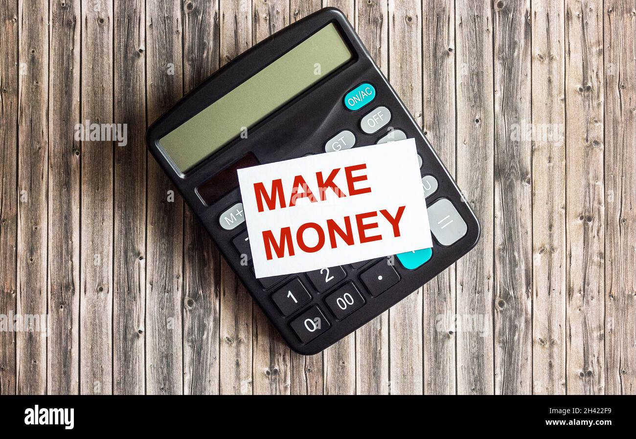 The calculator lies on a wooden table. On the sticker the text Earn Money. Stock Photo