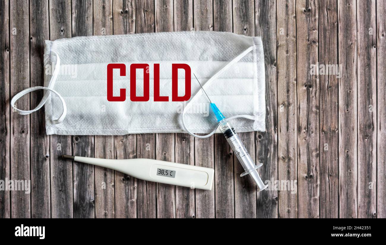 Cold season concept. The text is coldly written on a medical mask. Stock Photo