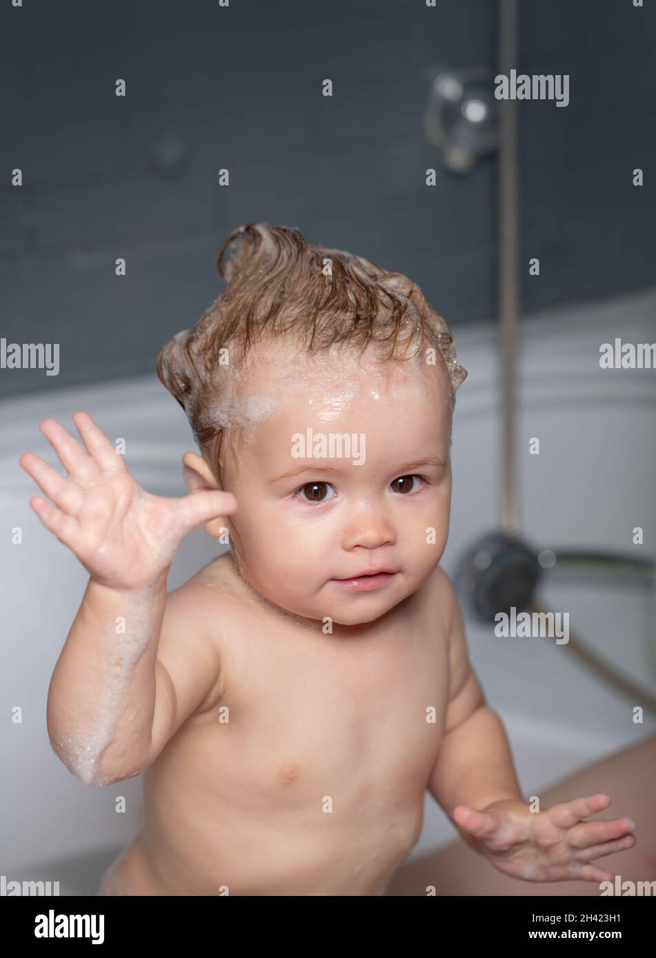 Baby child washing in a bathtub with foam. Kid bathing in bathroom