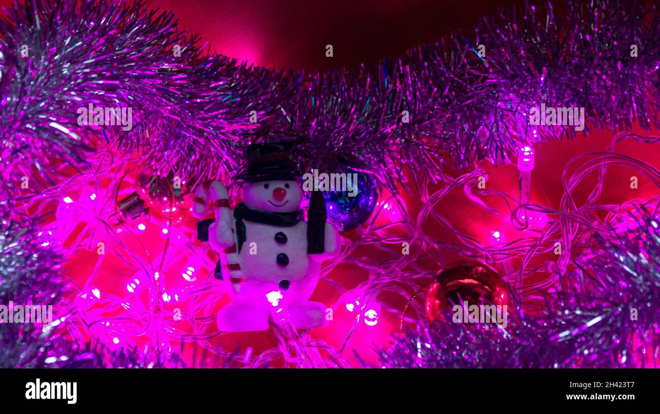 Frame of Christmas lights on a purple background with a toy snowman