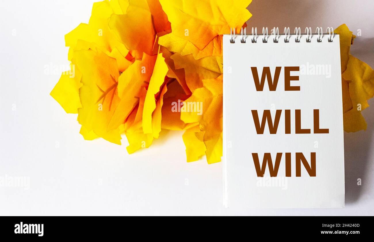 We will win, text on notepad white background, yellow foliage in the background Stock Photo
