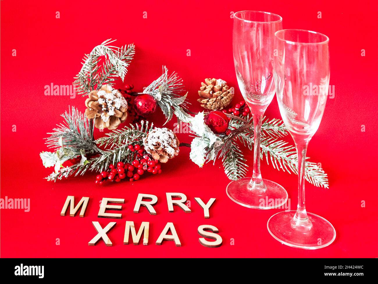 Text Merry Christmas made from wooden letters. Two glasses with