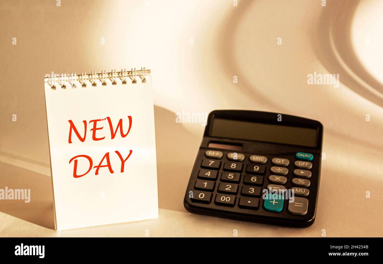 Calculator and notepad with the text NEW DAY, on a white background. Stock Photo