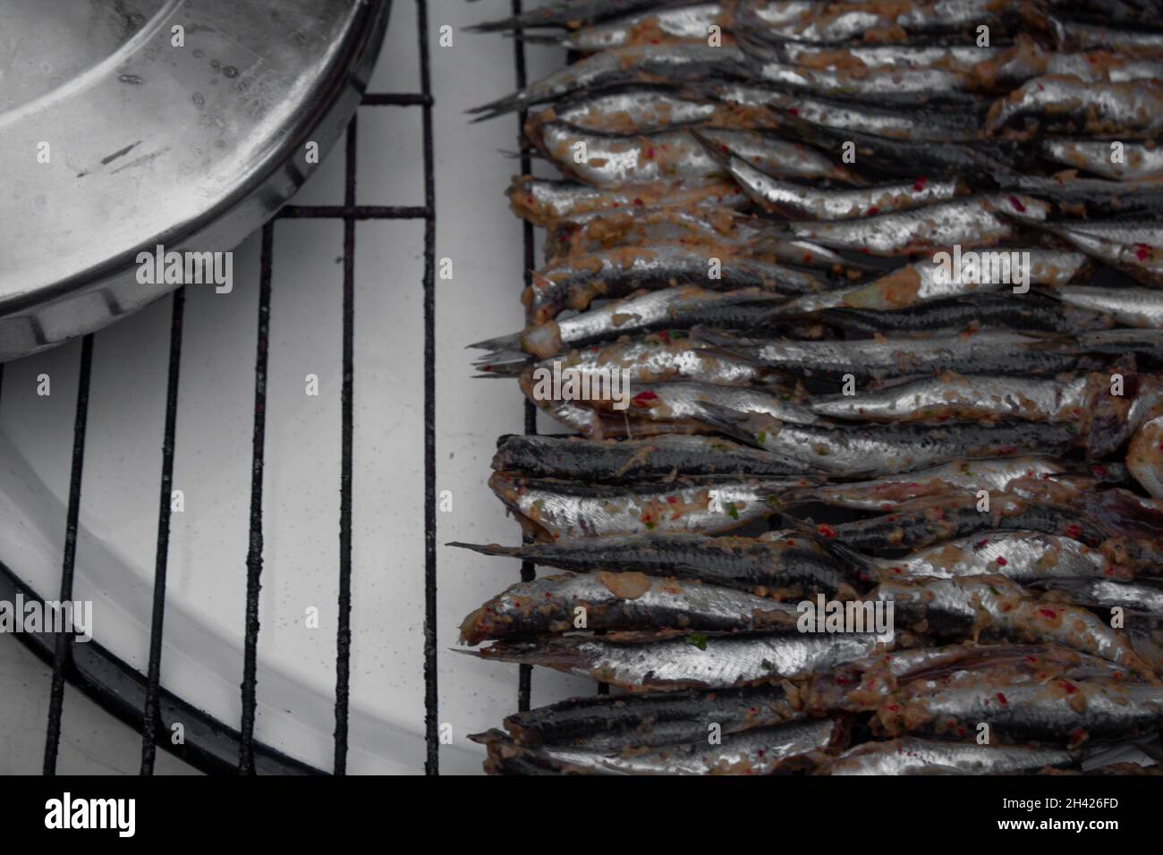 Preparation for grilling anchovies on charcoal. Ordered fishes in rows