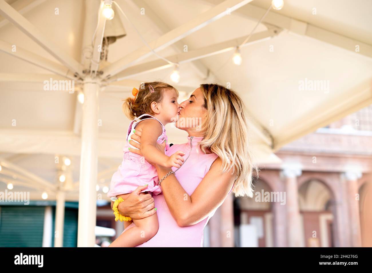 Happy loving family - Beautiful blond mother hugging and  kissing her sweet daughter on street in the trip - Family, motherhood and people concept Stock Photo