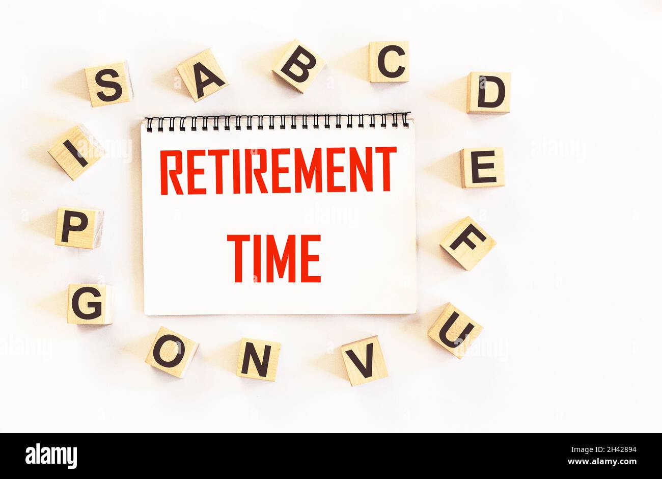 Pension time written on a notebook and a white background, next to letters on cubes. The concept of retirement age Stock Photo