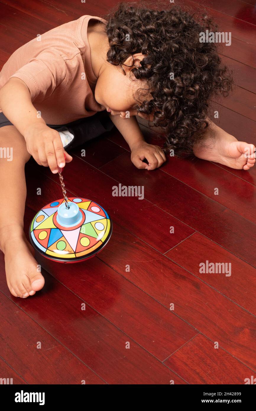 2 year old toddler boy learning how to operate toy to top, pressing down to make it spin Stock Photo