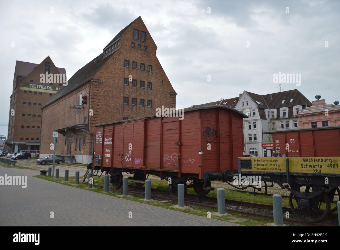 Old freight wagon of the GDR Reichsbahn, and warehouse Building in Rostock, Germany. Stock Photo