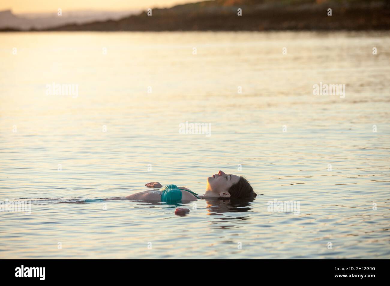A woman lying on her back floating in cold sea water Stock Photo