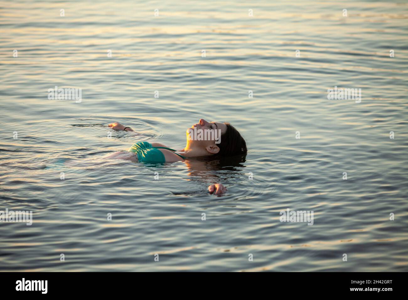 A woman lying on her back floating in cold sea water Stock Photo