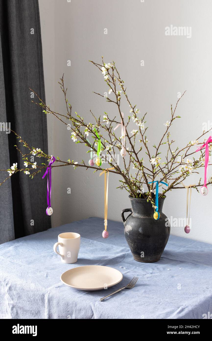 Blooming cherry branches decorated with colorful ribbons with easter eggs, Happy Easter, table setting Stock Photo