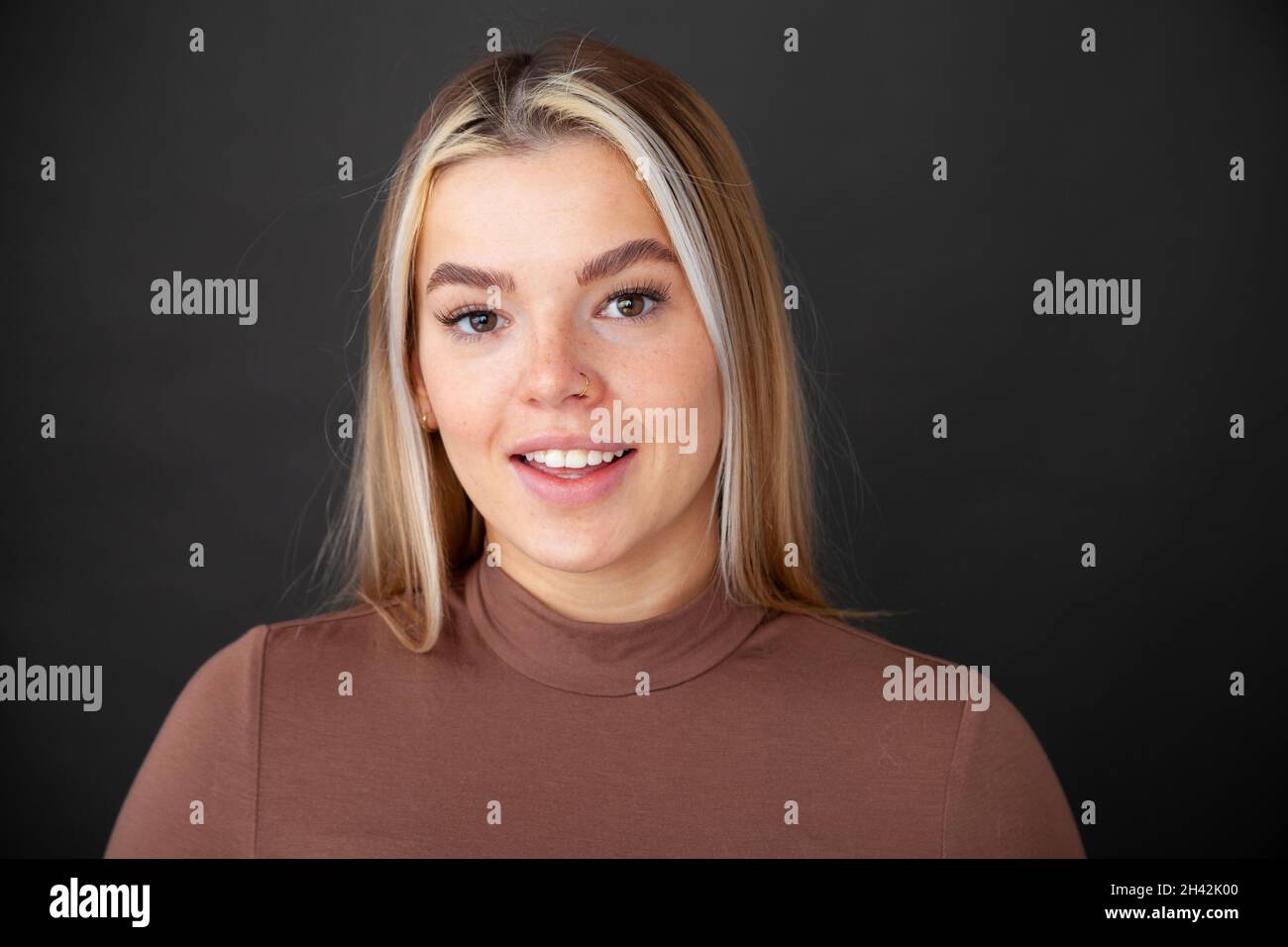 A beautiful young woman giving a toothy smile towards camera Stock Photo