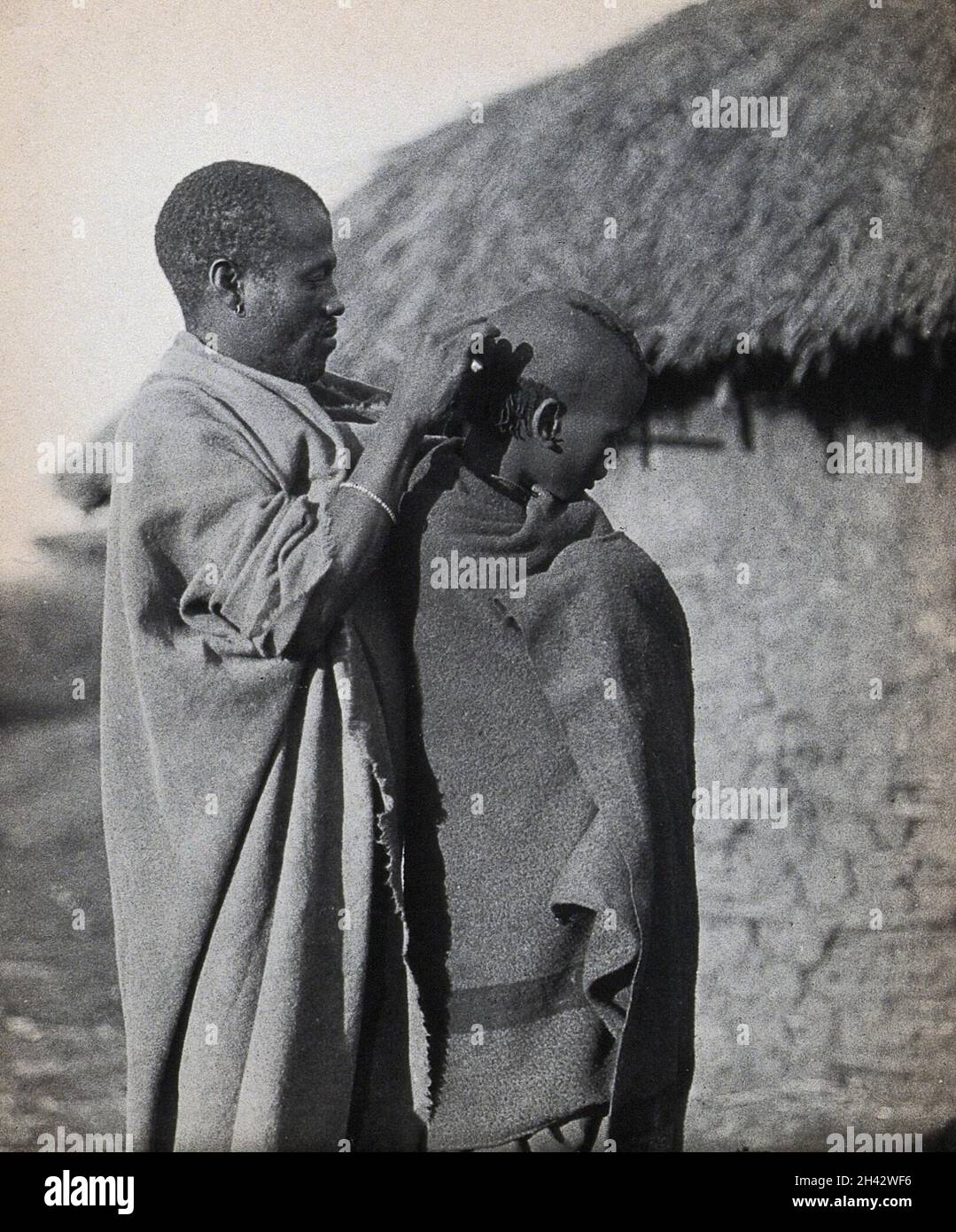 South Africa: a Pondo tribesman attends to the hairstyle of a fellow tribesman. Photograph, ca. 1900. Stock Photo