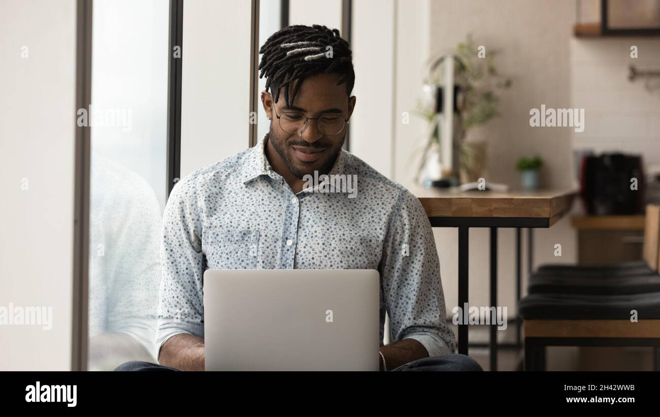 Happy young male african american freelancer working on computer. Stock Photo
