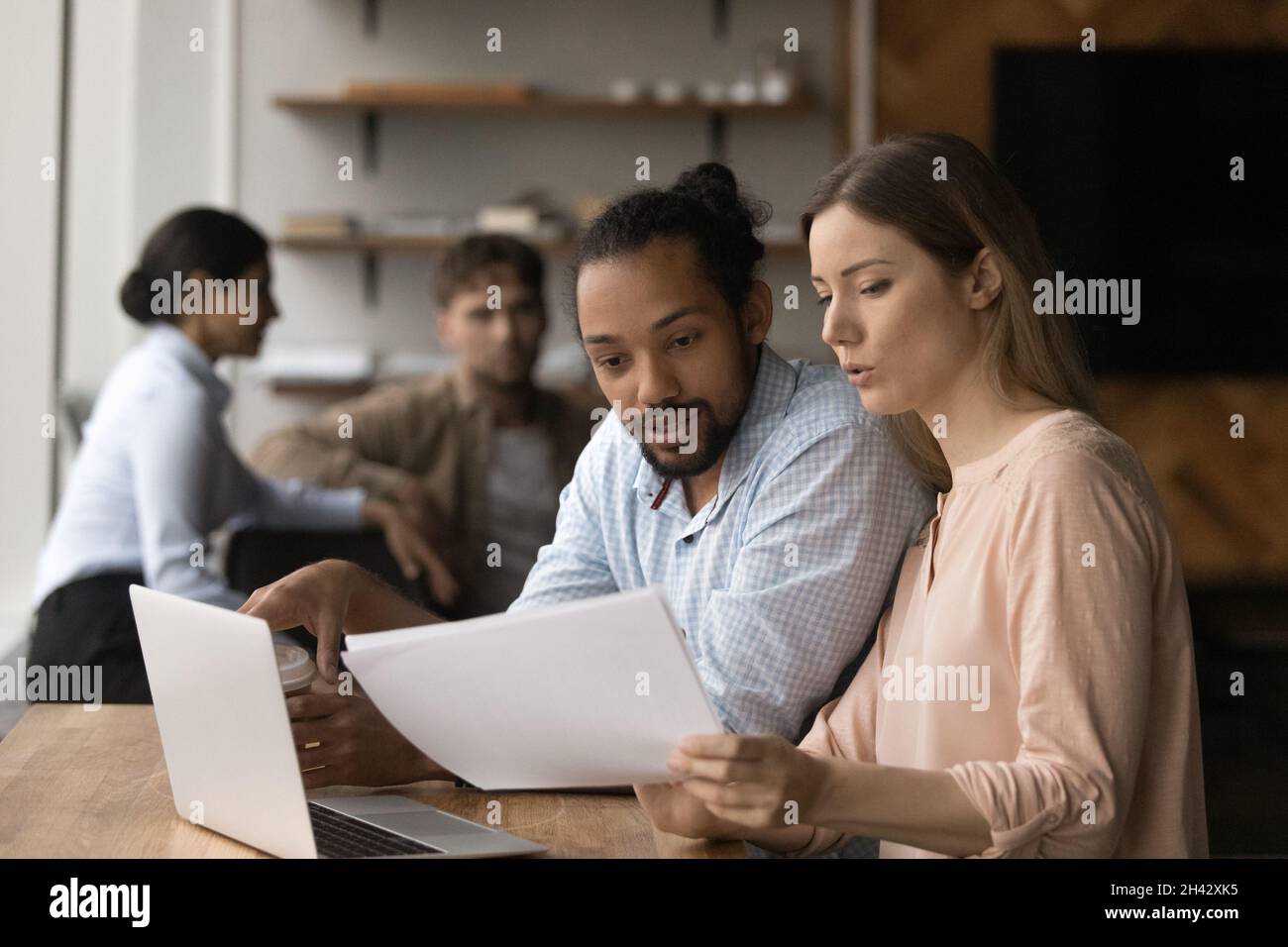 Concentrated mixed race colleagues analyzing paper report. Stock Photo