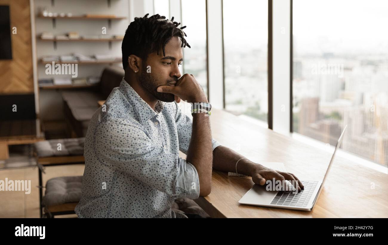 Thoughtful young mixed race businessman working on project. Stock Photo