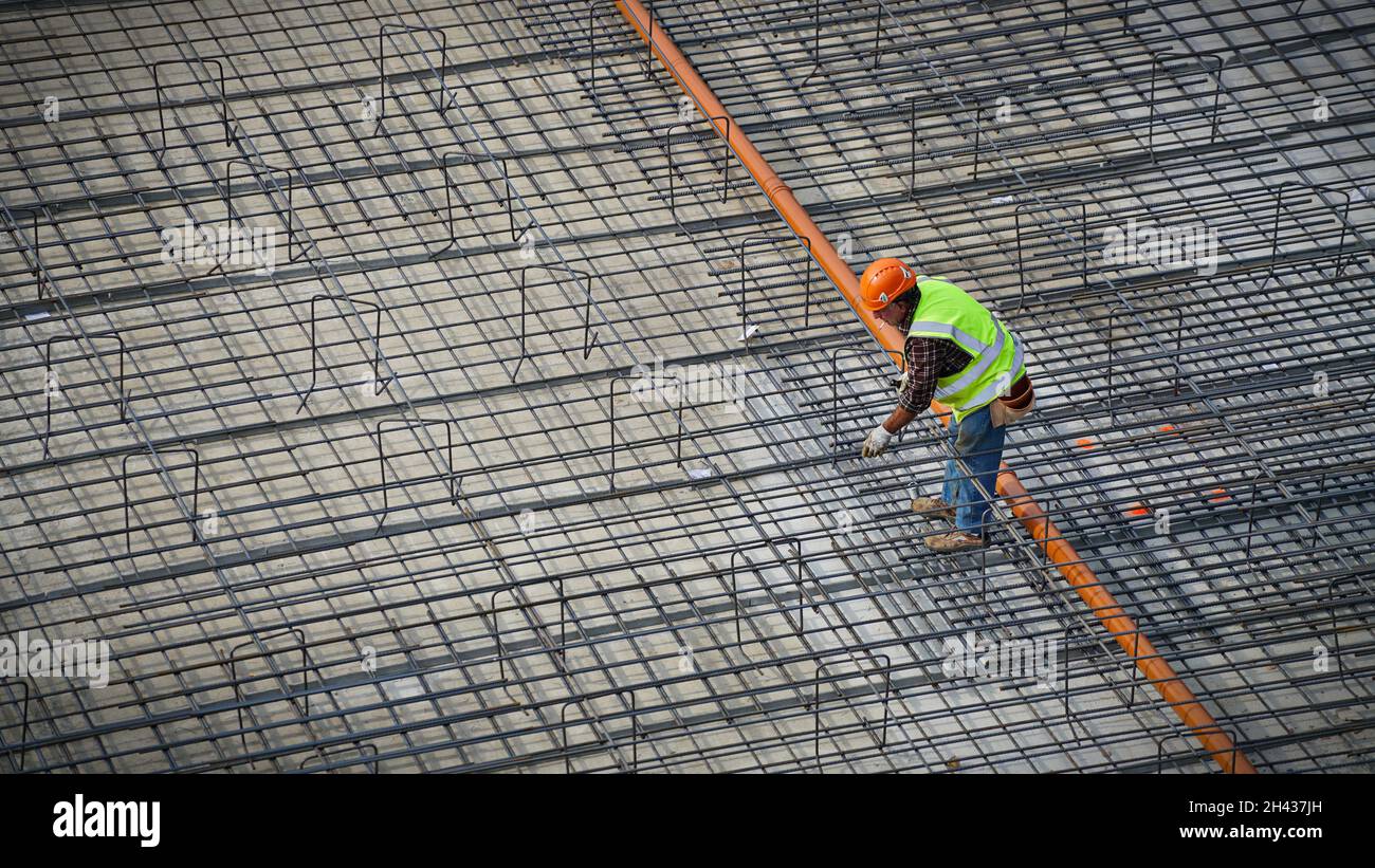 Construction workers assembling steel reinforcement bars on the site of a new building. Milan, Italy - October 2021 Stock Photo