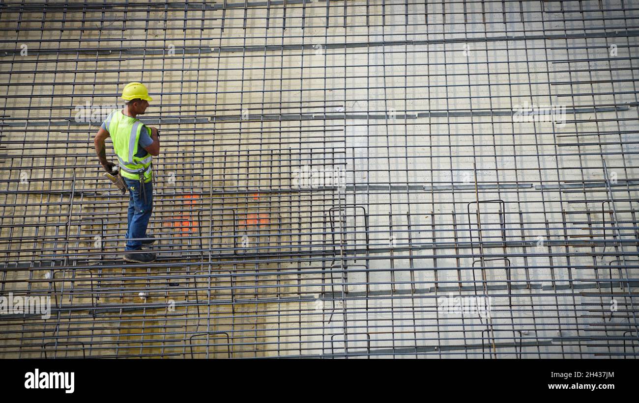 Construction workers assembling steel reinforcement bars on the site of a new building. Milan, Italy - October 2021 Stock Photo