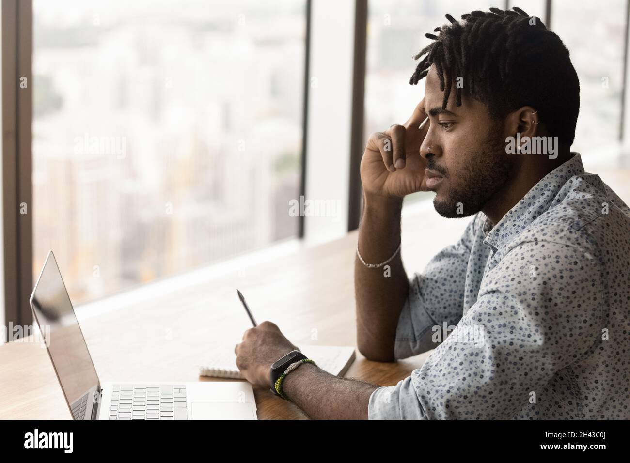 Thoughtful young brazilian man working on computer. Stock Photo