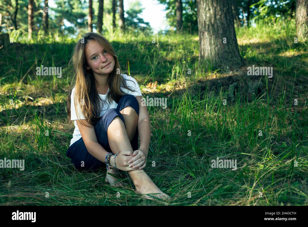 Teen girl sitting on the green grass in the park in the summer Stock ...