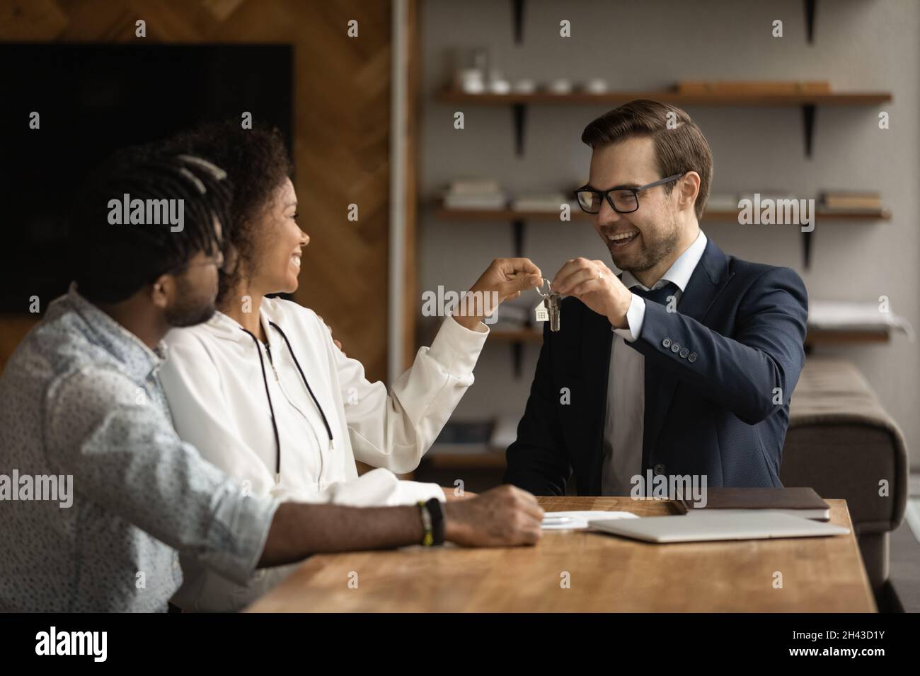 Happy male realtor giving keys to african american clients Stock Photo ...