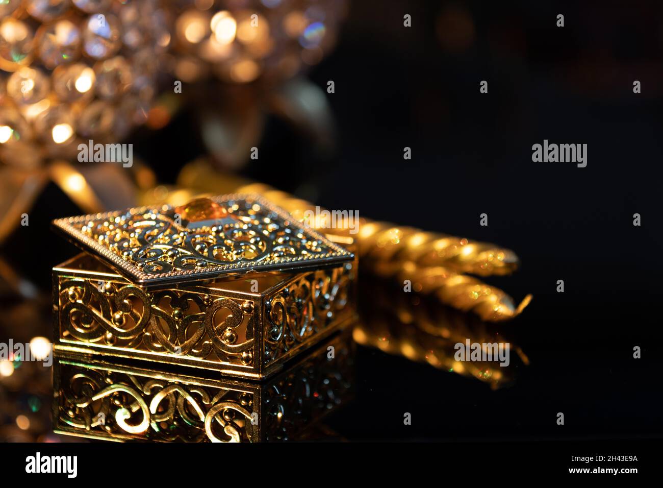Gift box with golden candle stick with and on a reflective base for Diwali deepawali dipawali lakshmi pooja or puja, with glittering background bokeh Stock Photo