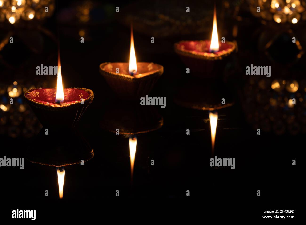 Glowing glittering Clay Diya Deep Dia lamps arranged or placed in a sequence pattern on a reflective base for Hindu festival Laxmi pooja Diwali, Stock Photo