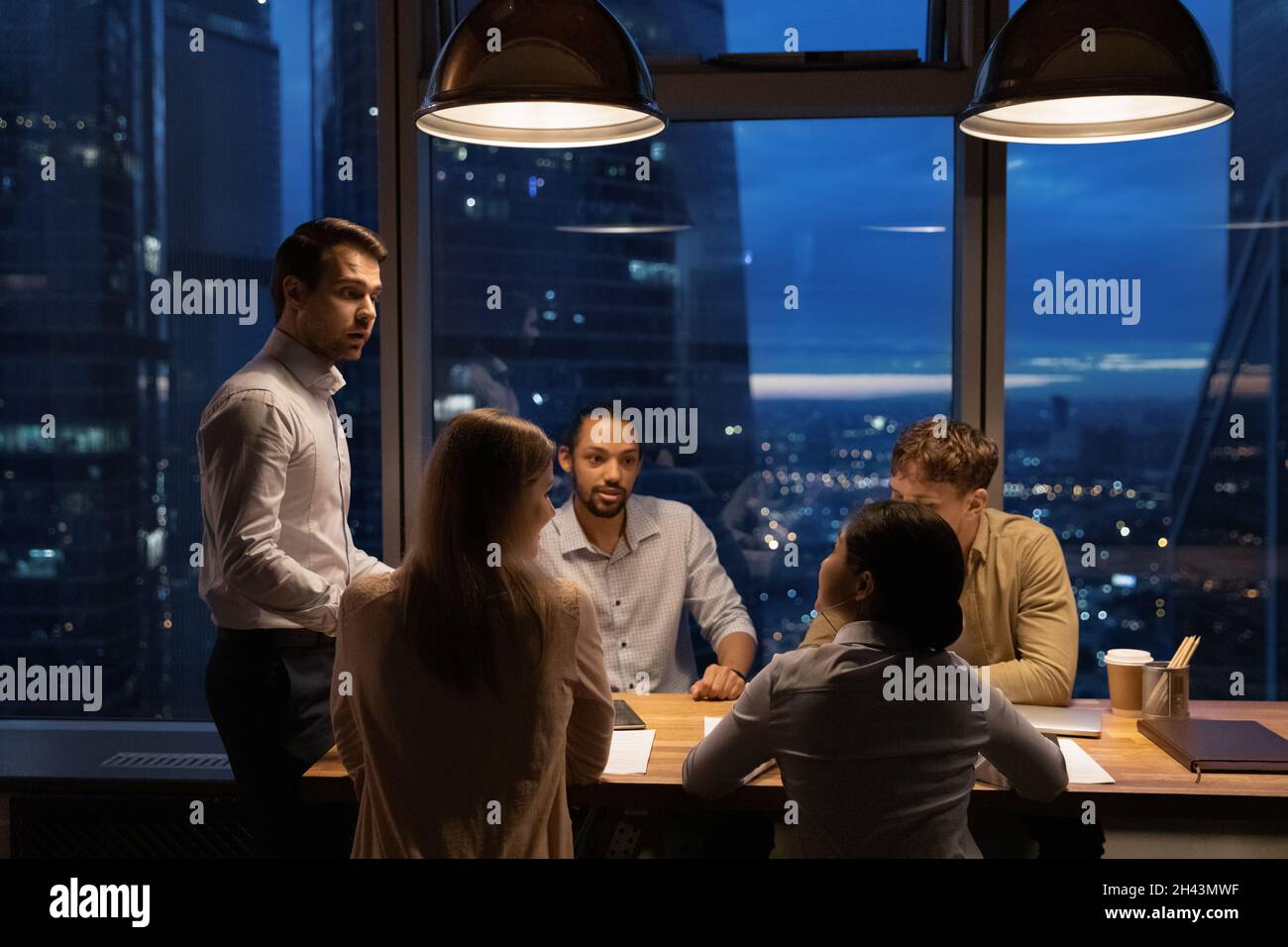Concentrated young mixed race employees discussing project ideas. Stock Photo