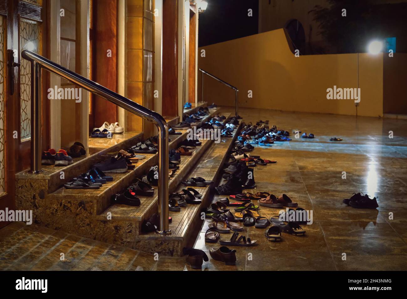 Muslims people take off shoes on steps of mosque entrance before friday evening prayers worship. Footwear outside mosque Stock Photo