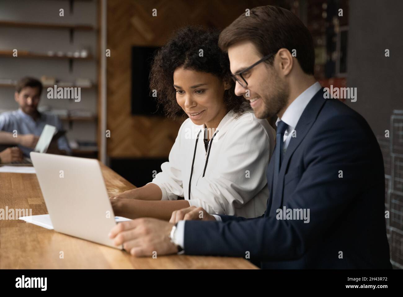 Happy young mixed race business people working on computer. Stock Photo