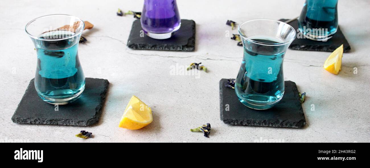 Healthy drinks, organic blue butterfly pea flower tea with limes and lemons, grey concrete background copy space top view Stock Photo