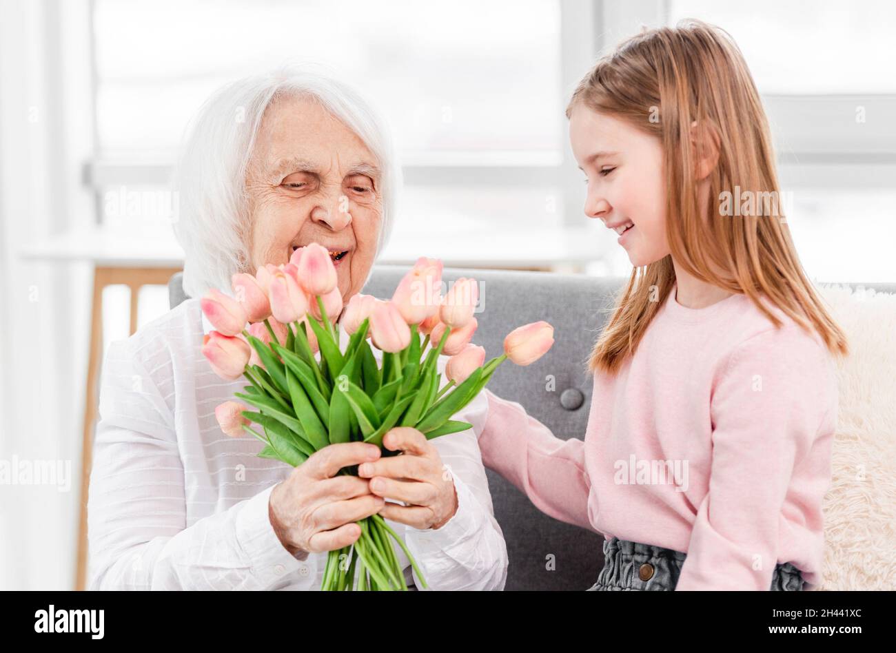 Grandaughter gives flowers to grandmother Stock Photo Alamy