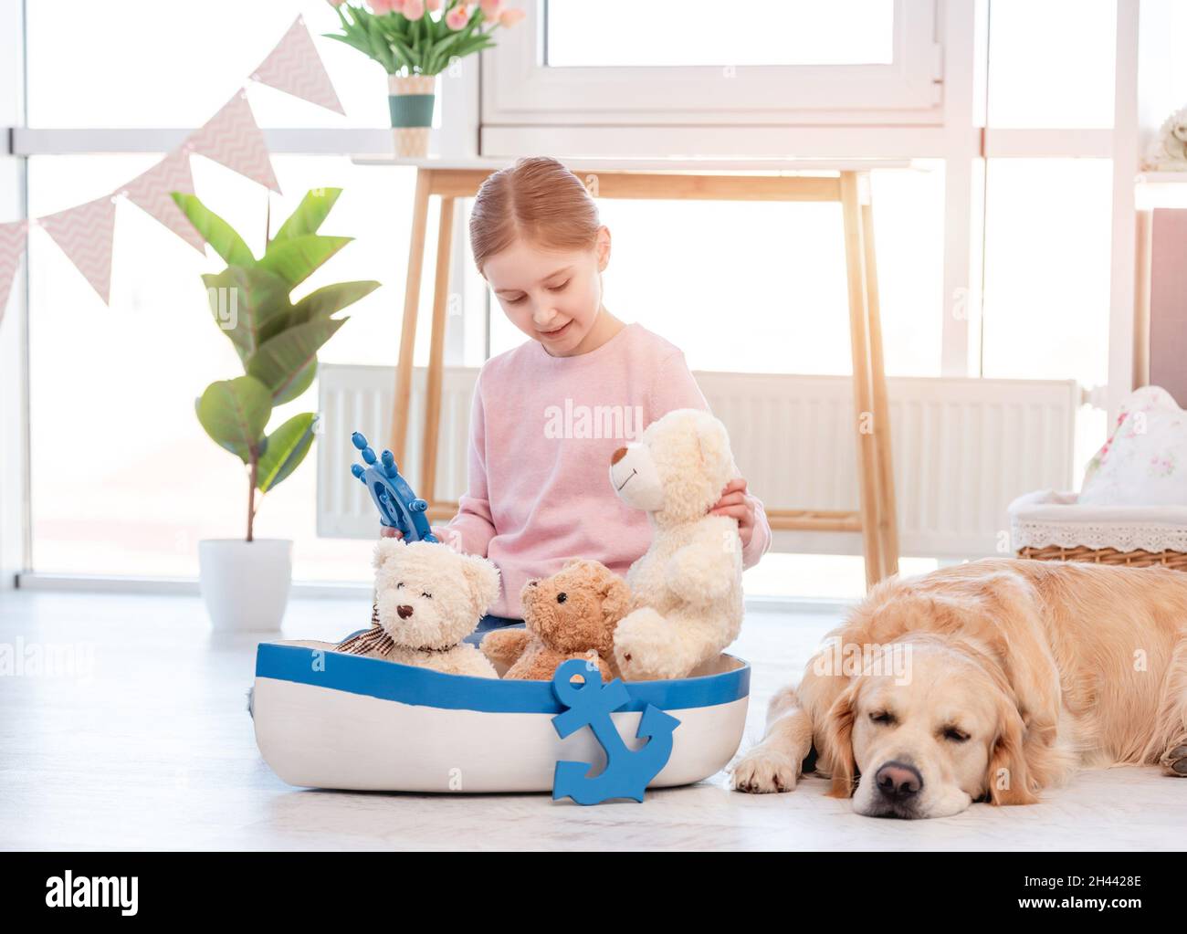 Little girl play with sea ship with golden retriever dog Stock Photo