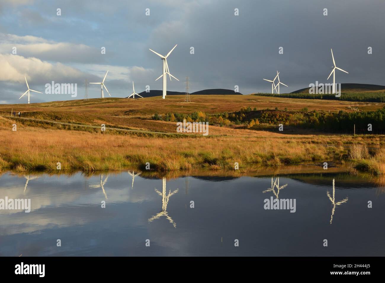 Wind turbines on a hillside by a small lake at Kilbraur Windfarm, Scottish Highlands Stock Photo