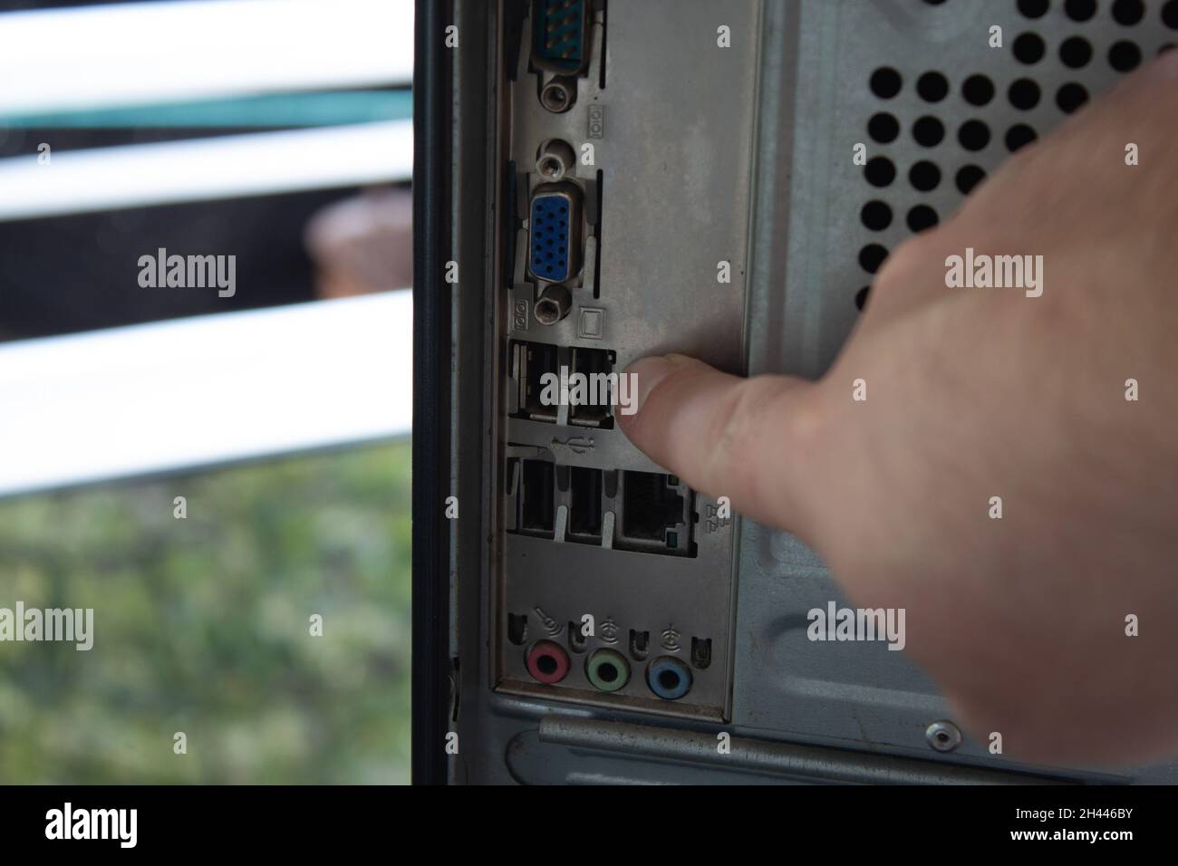 Pointing out the back sockets of a home computer with finger. Stock Photo