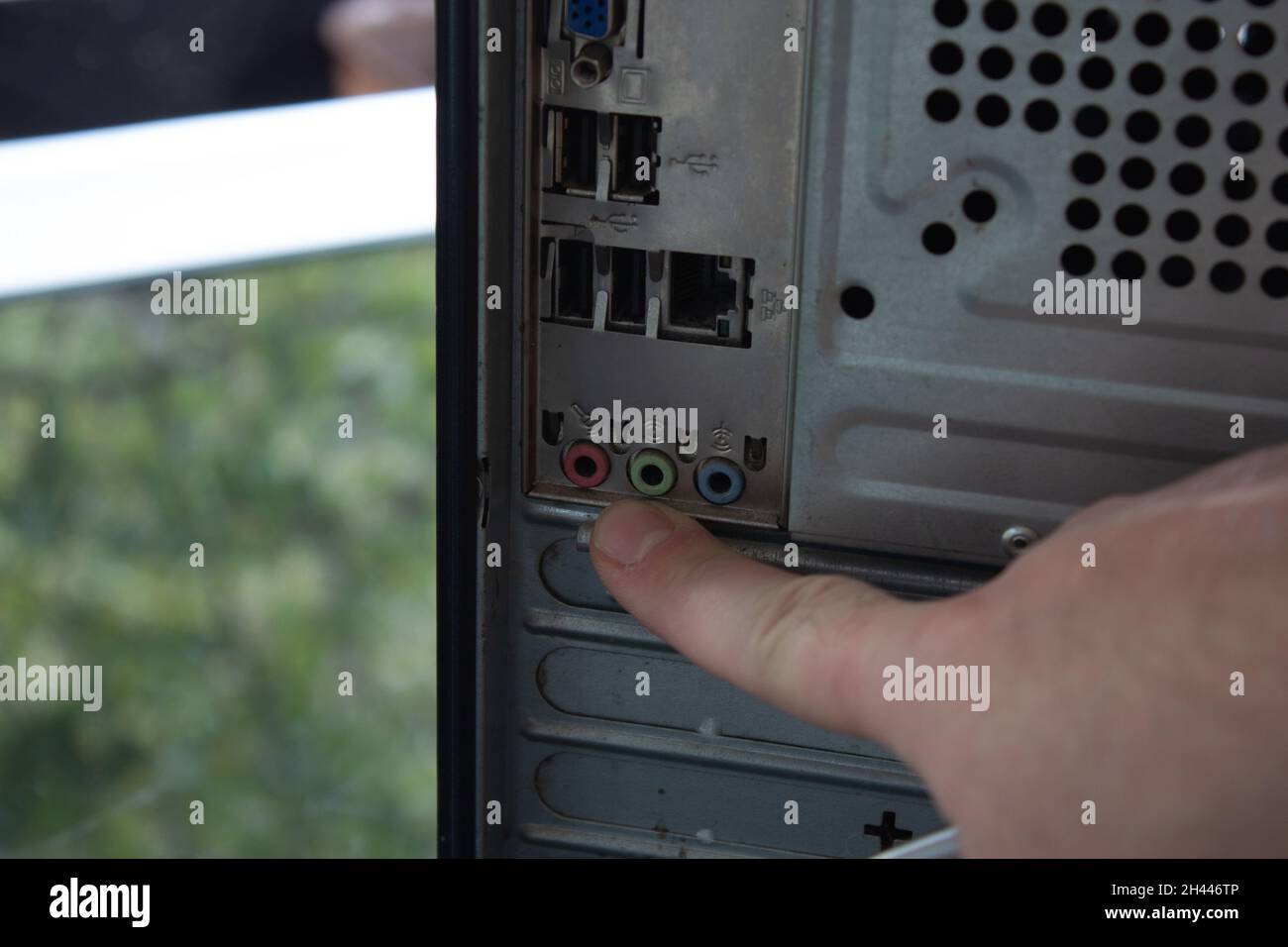 Pointing out the back sockets of a home computer with finger. Stock Photo