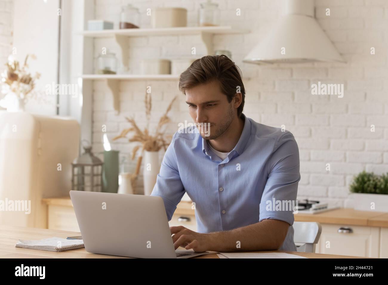 Handsome thoughtful man sit at table working on laptop Stock Photo