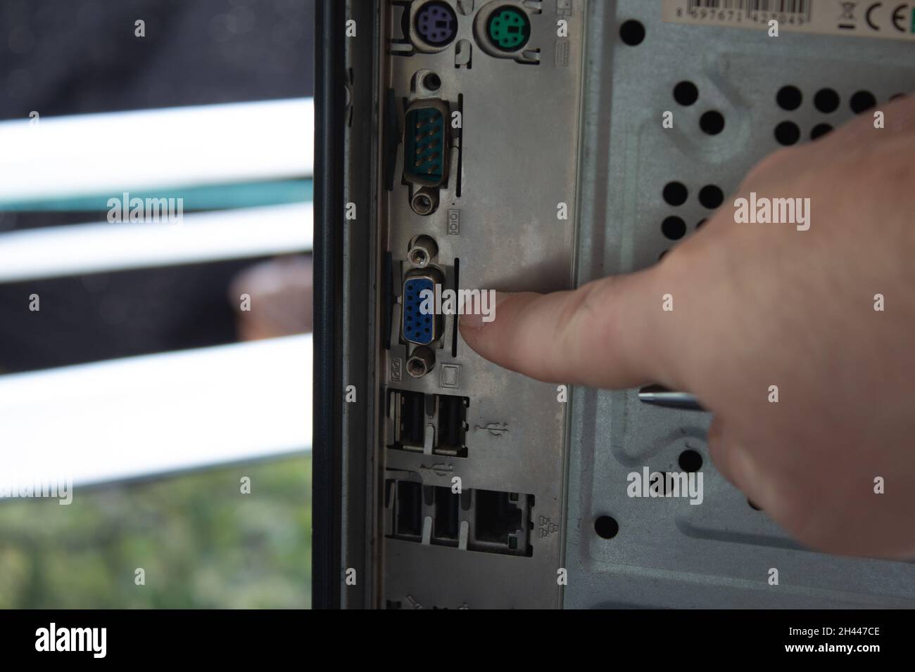 Pointing out the back sockets of a home computer with finger. Stock Photo