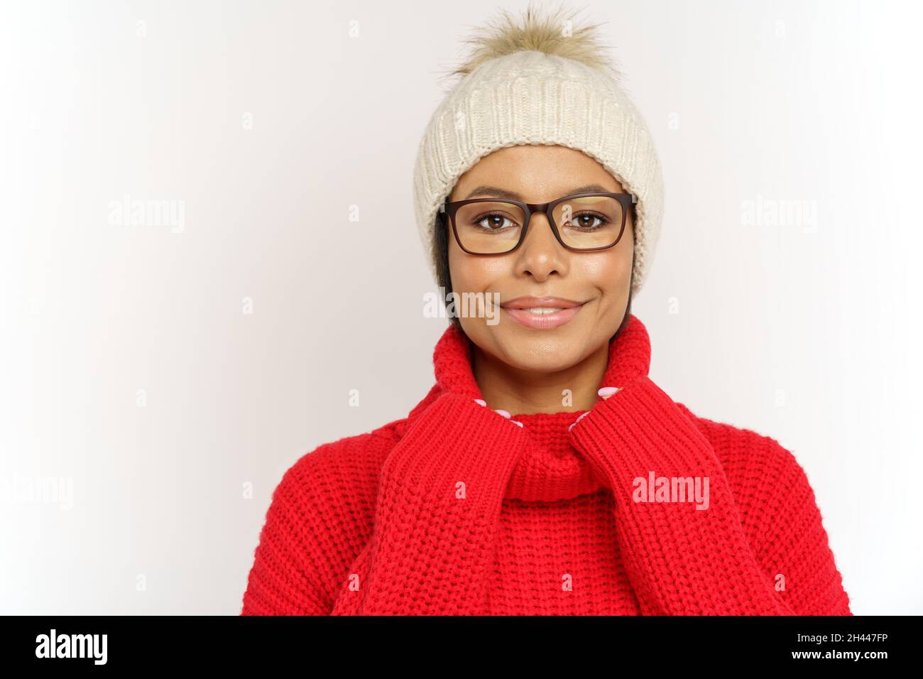 Happy black female in winter clothes, hat and cozy knitted sweater ready for cold season outdoors Stock Photo