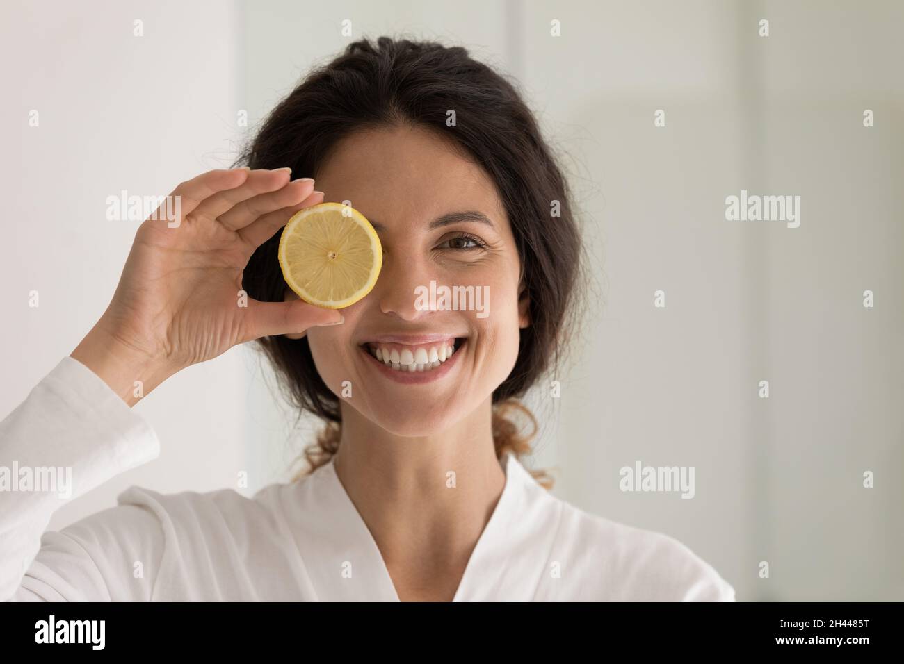 Beautiful woman holds lemon slice, cover eye look at camera Stock Photo