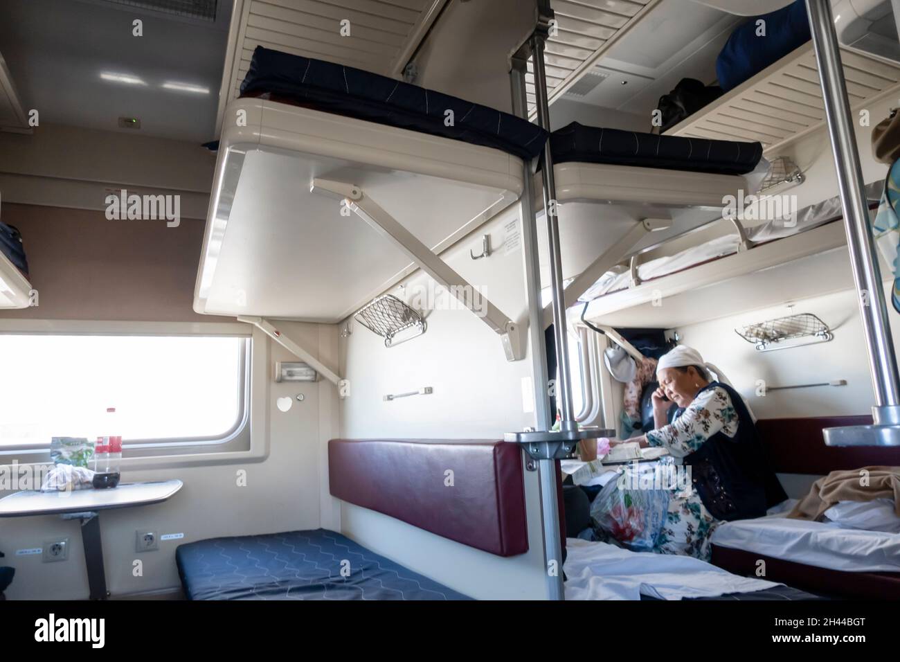 Elderly Kazakh woman sitting in the 3 class car, platzcart carriage in the train operated by Kazakhstan Temir Zholy Stock Photo
