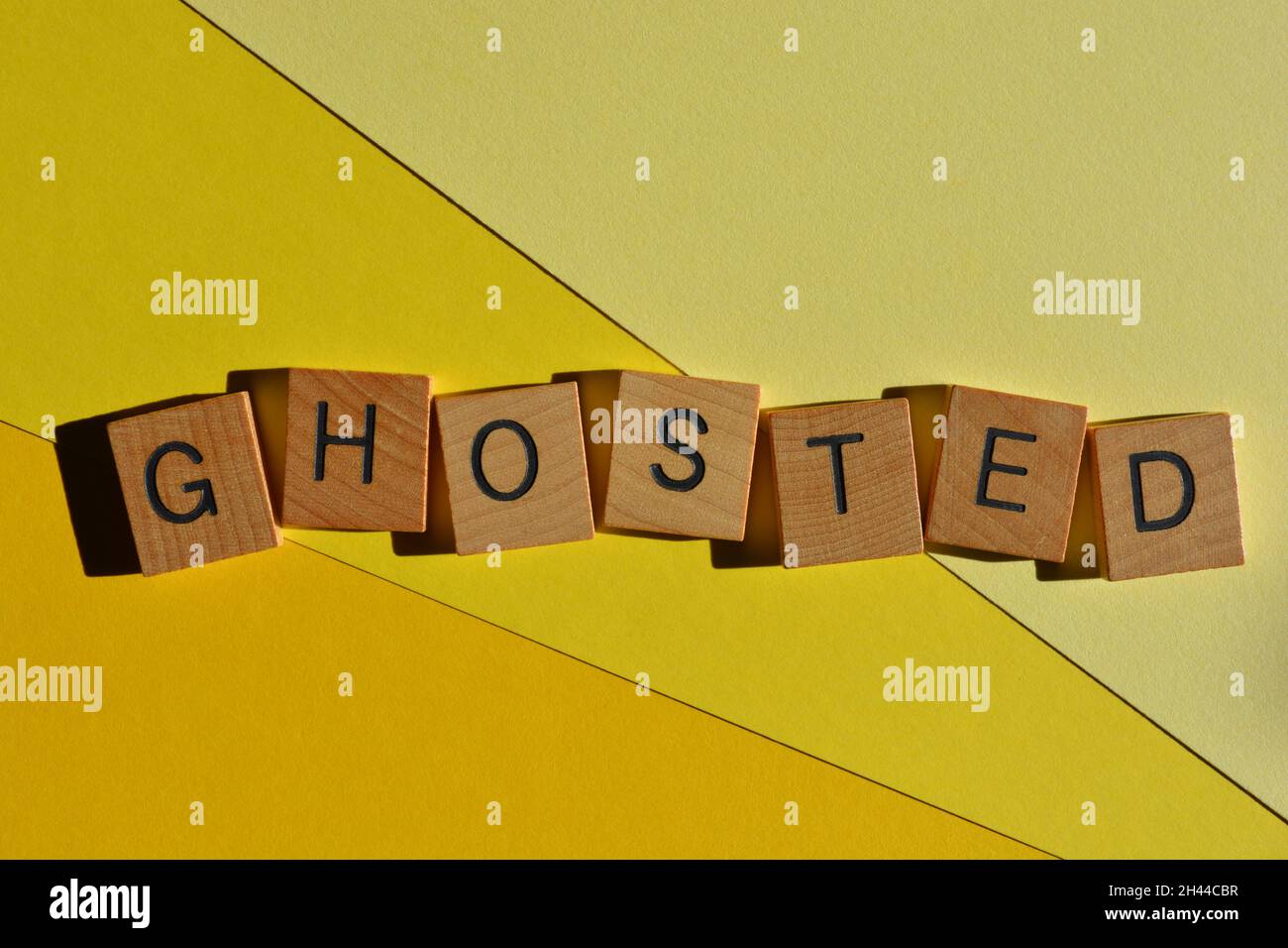 Ghosted, word in wooden alphabet letters isolated on yellow background, meaning to stop communicating with someone out of the blue Stock Photo