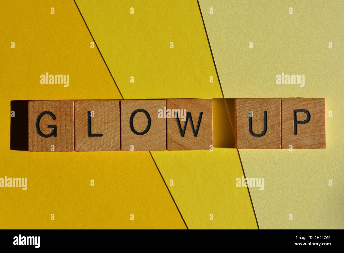 Glow Up, words in wooden alphabet letters isolated on yellow. Gen Z slang, meaning to go through a positive physical, mental or spiritual change Stock Photo